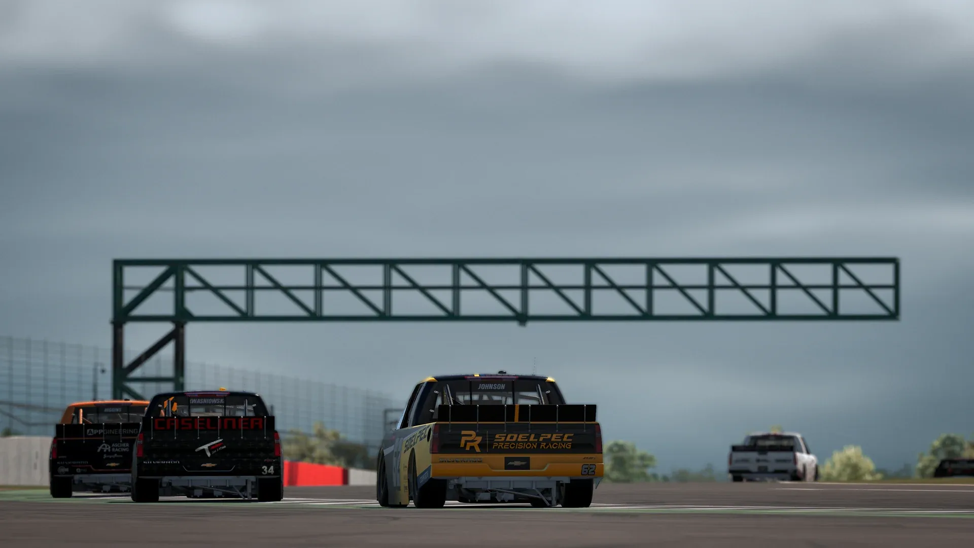 NASCAR trucks viewed from behind under grey skies at Silverstone during VCO INFINITY 2026 on iRacing.